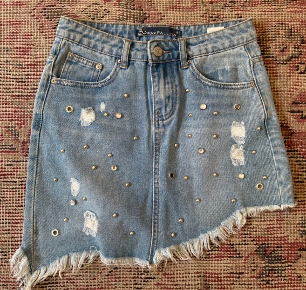 Farafallina asymmetrical denim skirt with gold studs and a raw hem. 
