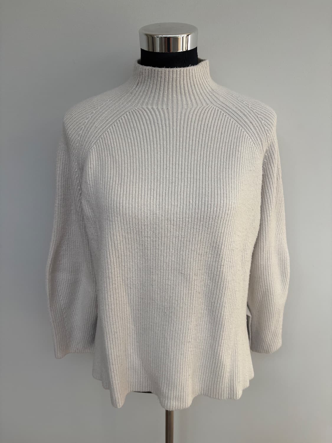 Cream ribbed knit with a mock neck with a small slit hem. Viscose blend .